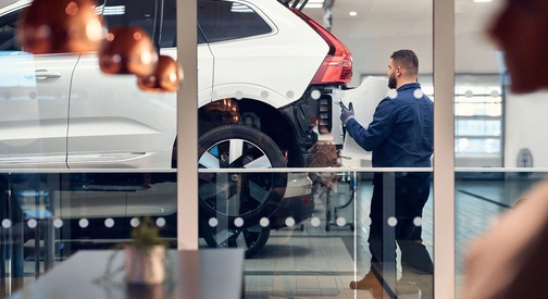 Un mécanicien Volvo change le bouclier arrière d'un SUV XC60 blanc