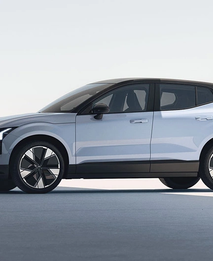 Vue latérale d’une Volvo EX30 blanche moderne avec toit noir et grandes roues, dans un décor minimaliste