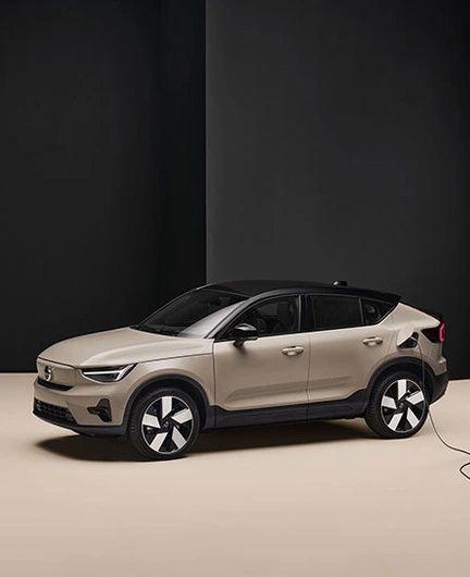 Volvo EC40 beige branché à une borne de recharge dans une pièce minimaliste noire et beige