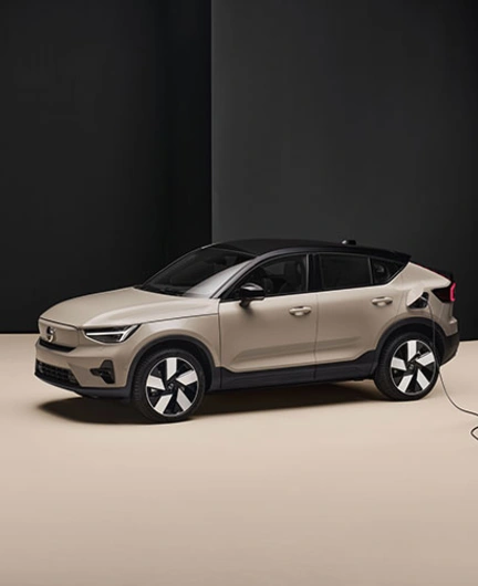 Volvo EC40 beige branché à une borne de recharge dans une pièce minimaliste noire et beige