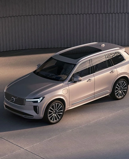 Volvo XC90 beige stationné sur une surface en béton, vu en plongée, avec design moderne et mur incurvé en arrière-plan