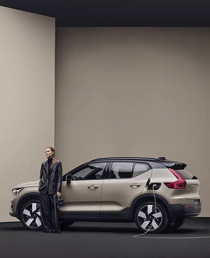 Femme à côté d’un EX40 beige branché à une borne de recharge