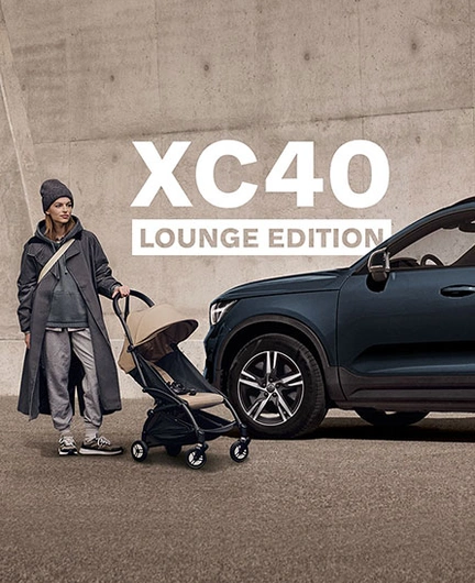Volvo XC40 Lounge Edition garé près d’une personne avec une poussette devant un mur en béton