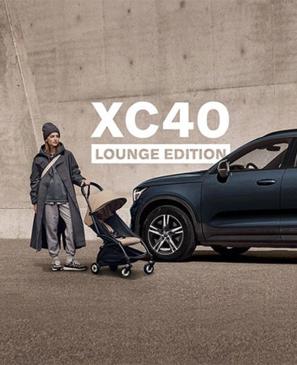 Volvo XC40 Lounge Edition garé près d’une personne avec une poussette devant un mur en béton