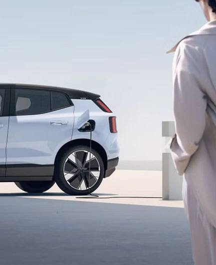 Volvo EX30 en charge, observé par une personne en manteau beige.