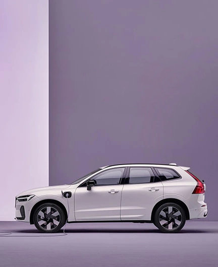 Volvo XC60 blanc branché à une borne de recharge sur fond violet