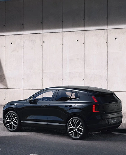 Volvo EX30 Black Edition garé le long d’un mur en béton sous une zone ombragée