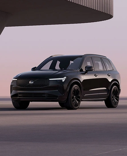 XC90 Black Edition vu de trois quart avant dans un décor moderne et minimaliste avec phares LED en forme de marteau de Thor allumés.