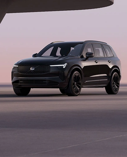 XC90 Black Edition vu de trois quart avant dans un décor moderne et minimaliste avec phares LED en forme de marteau de Thor allumés.