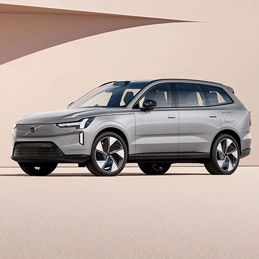 Volvo EX90 argenté garé devant un mur beige avec une ombre projetée