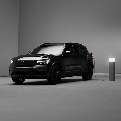 EX40 Black Edition en charge dans une pièce minimaliste, faiblement éclairée, aux murs et sol gris