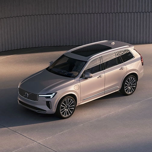 Volvo XC90 beige stationné sur une surface en béton, vu en plongée, avec design moderne et mur incurvé en arrière-plan