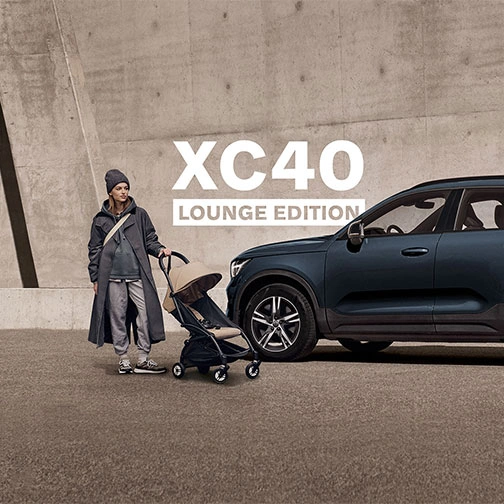 Volvo XC40 Lounge Edition garé près d’une personne avec une poussette devant un mur en béton