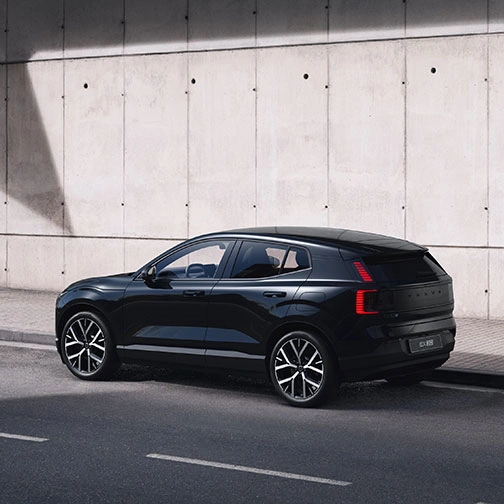 Volvo EX30 Black Edition garé le long d’un mur en béton sous une zone ombragée