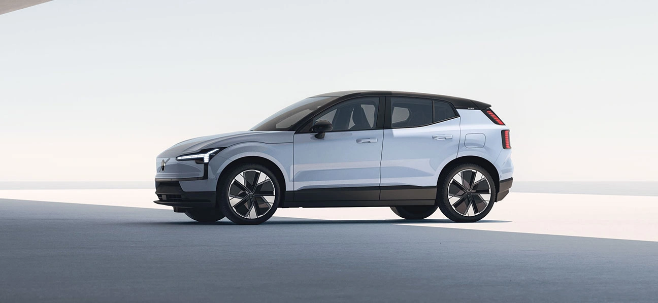 Vue latérale d’une Volvo EX30 blanche moderne avec toit noir et grandes roues, dans un décor minimaliste