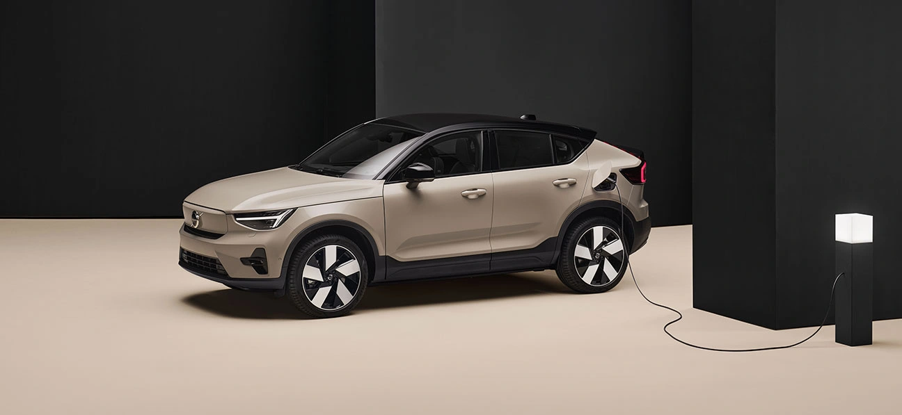 Volvo EC40 beige branché à une borne de recharge dans une pièce minimaliste noire et beige