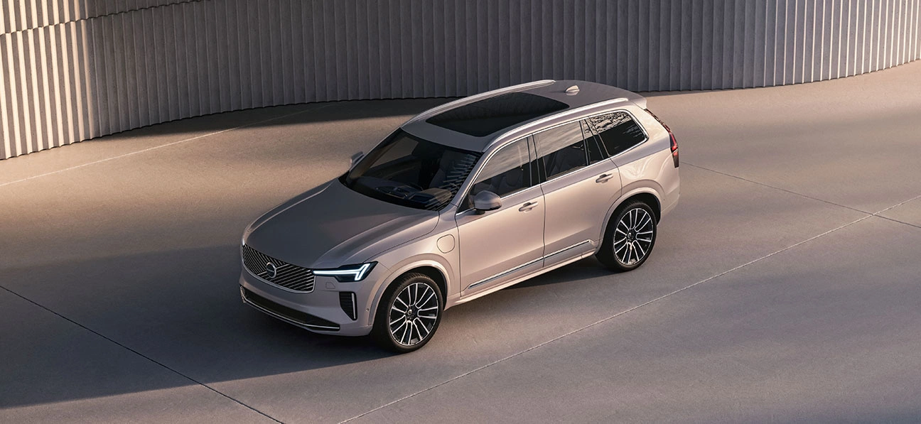Volvo XC90 beige stationné sur une surface en béton, vu en plongée, avec design moderne et mur incurvé en arrière-plan