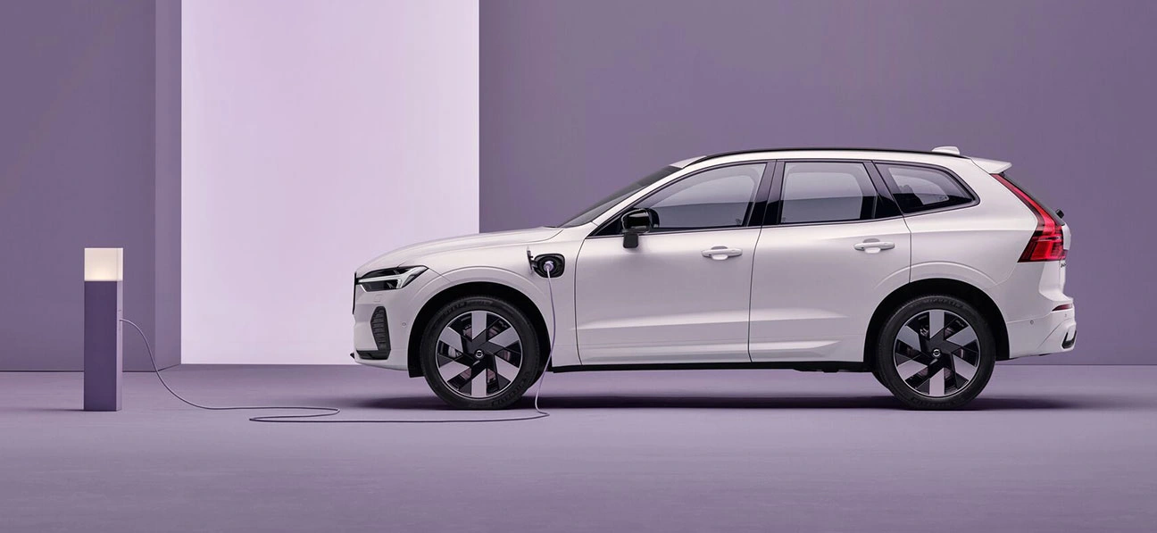 Volvo XC60 blanc branché à une borne de recharge sur fond violet