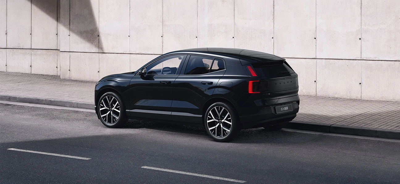 Volvo EX30 Black Edition garé le long d’un mur en béton sous une zone ombragée