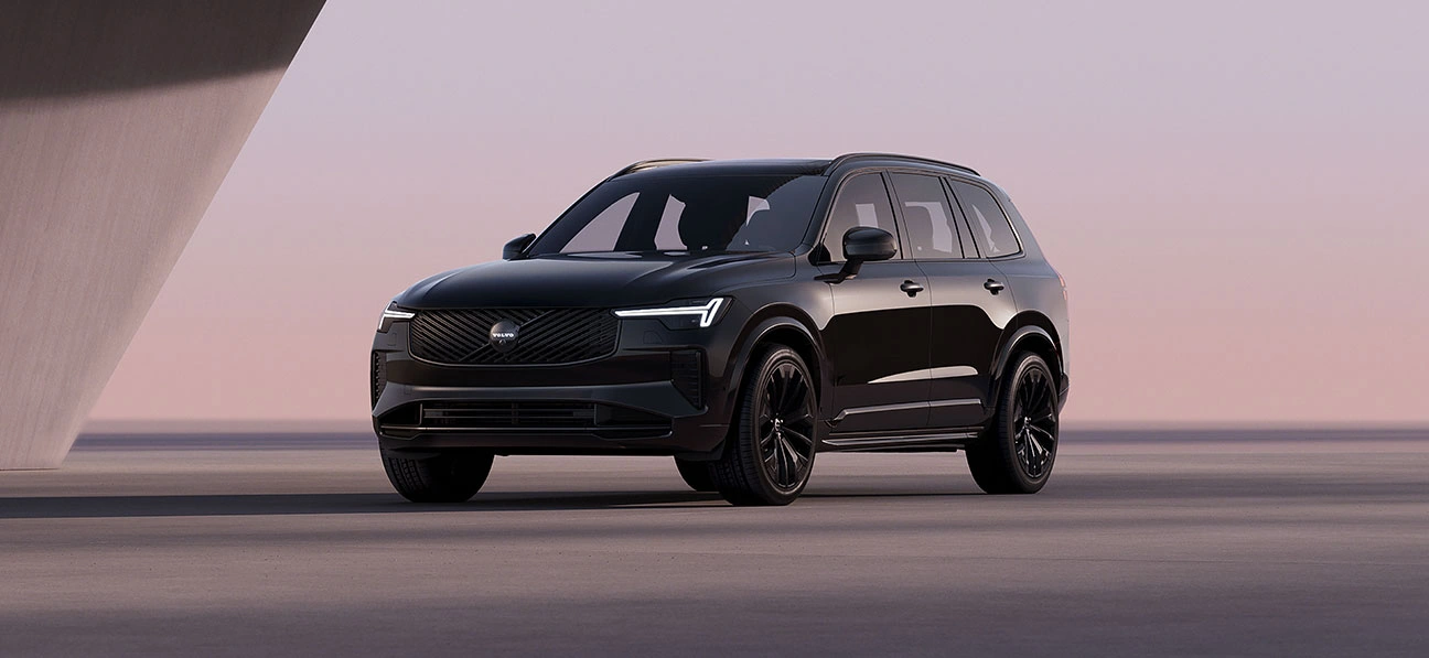 XC90 Black Edition vu de trois quart avant dans un décor moderne et minimaliste avec phares LED en forme de marteau de Thor allumés.