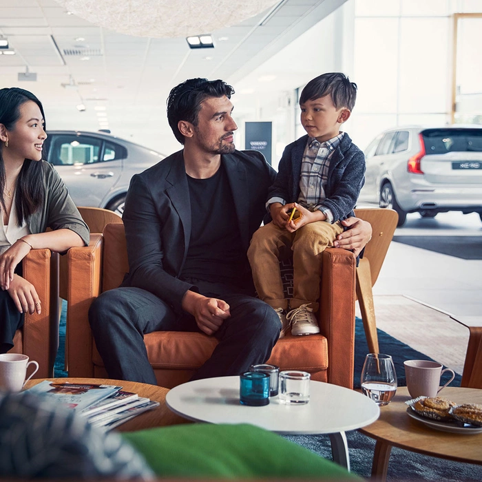 Famille assise sur un canapé dans une concession Volvo