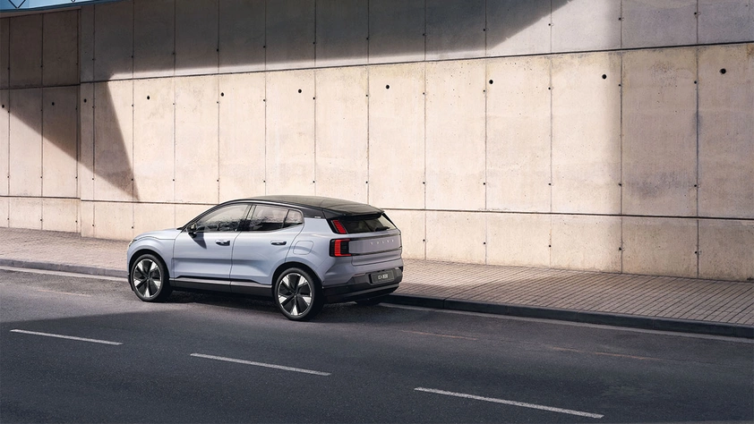 Volvo EX30 100% électrique bleu clair sur la route avec en fond un mur en ciment beige clair