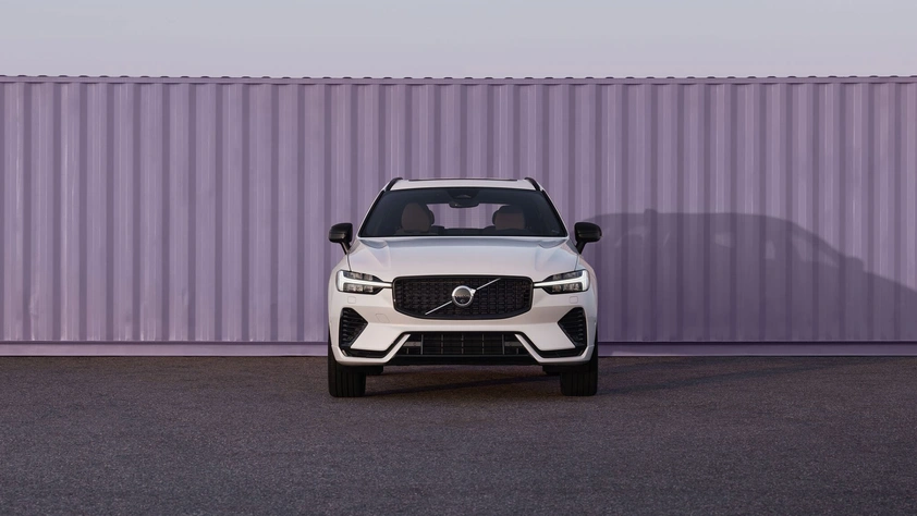 SUV Volvo blanc garé devant un grand conteneur violet sur une surface en asphalte.
