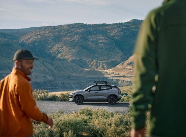 Voiture EX30 Cross Country dans la nature avec deux personnes qui se dirigent vers ce petit SUV 100% électrique