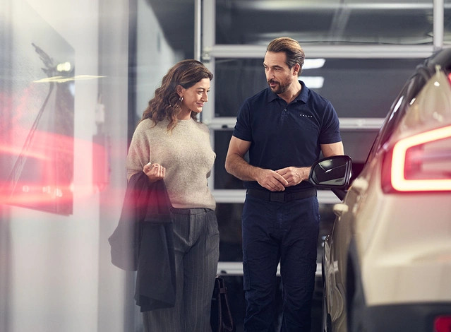 Dans un atelier Volvo, un technicien échange avec une cliente et lui présente le programme Les privilèges V+