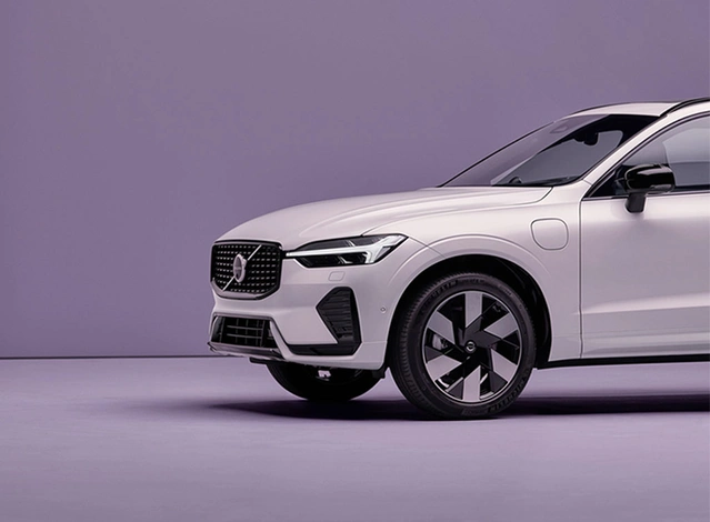 Vue partielle d’un SUV Volvo blanc dans une pièce minimaliste violette.